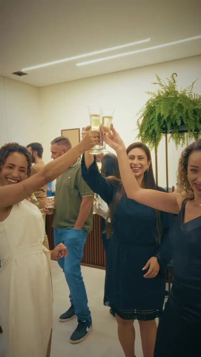 Grupo de convidados erguendo taças em um brinde durante a inauguração do escritório.