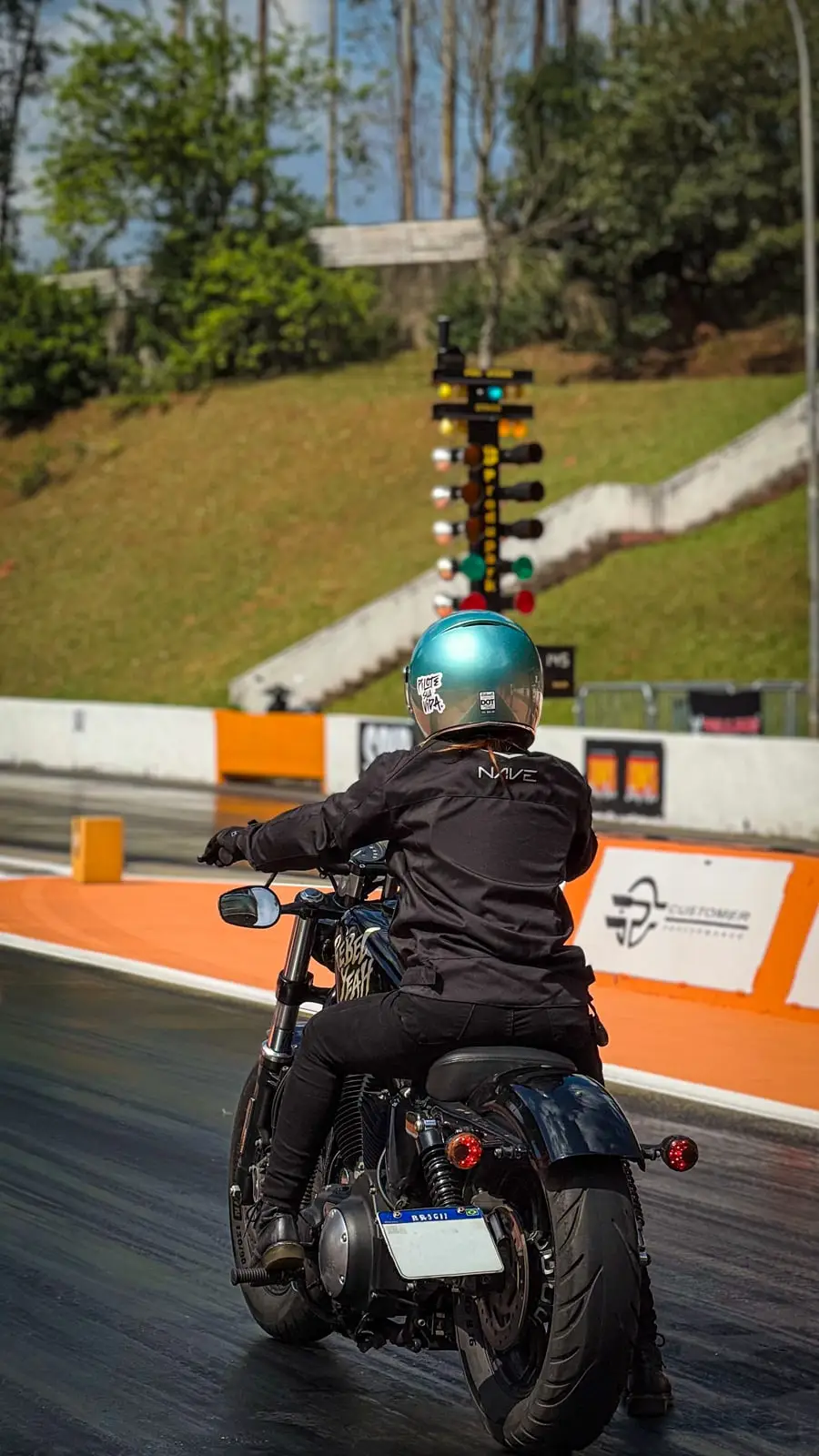 Piloto parado na linha de largada, ao lado da árvore de luzes que dá a partida.