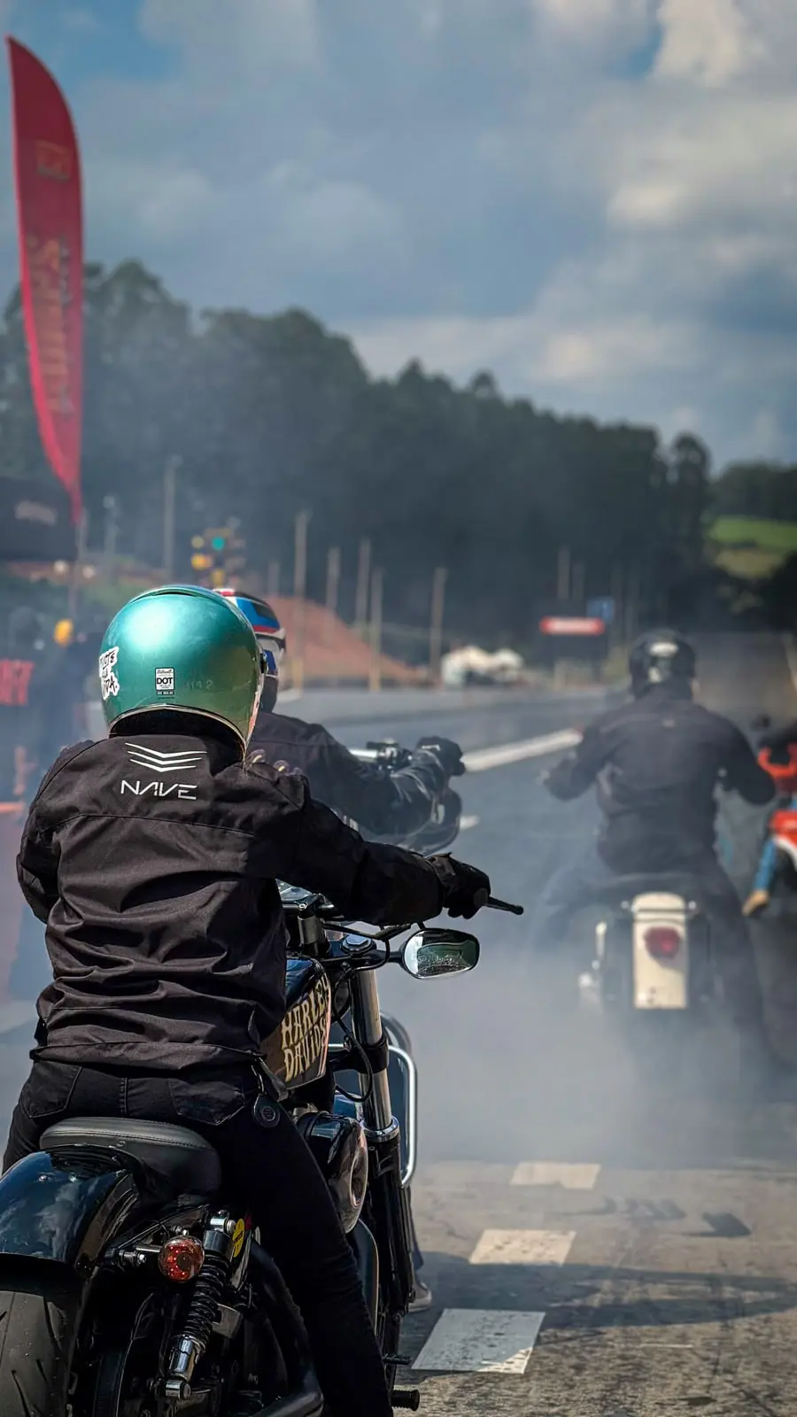 Pilotos alinhados na largada com a fumaça branca do aquecimento de pneu cobrindo o fundo da pista.